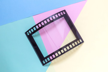 Photography picture frame in shape of vintage photo movie film strip negative on multicolored background minimalistic concept.
