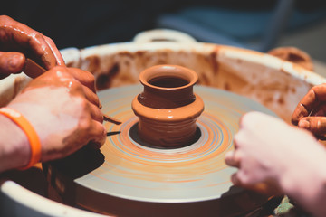 A process of pottery, with two people involved, working on pottery wheel and making clay pot