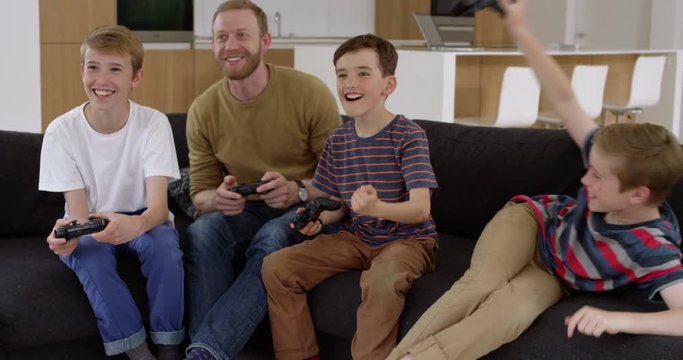 Handsome man and three children play on games console in contemporary modern home, in slow motion