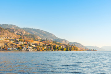 Waterfront homes and mountains on lake with blue sky and warm light from evening sunshine in autumn