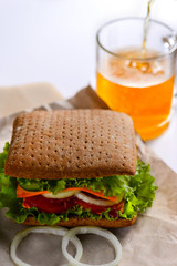 Sandwich with grain bread in and beer on white background