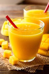 Mango smoothie in glass on dark wooden background