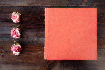 Brown wedding album with rose flowers decoration on brown wooden background