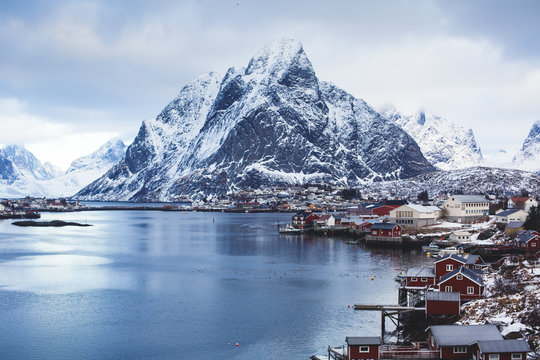 Beautiful super wide-angle winter snowy view of Reine, Norway, Lofoten Islands, with skyline, mountains, famous fishing village with red fishing cabins, Moskenesoya, Nordland