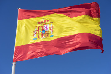 Flag of Spain in the wind on a mast on a sunny day. blue sky background