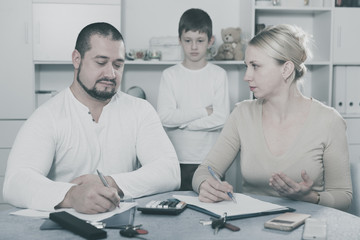 Parents calculating family budget while son standing behind