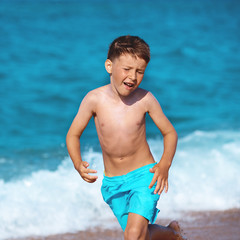 Caucasian boy at the seacost. He is running along the seaside wth his eyes beeing closed.
