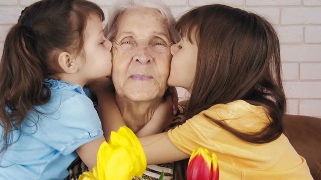 Happy old age. Children kiss grandmother.