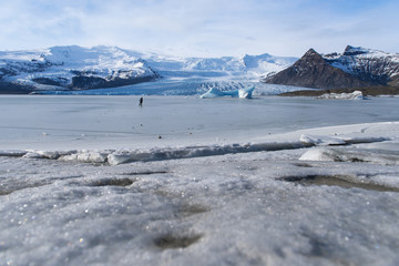 man in black dress walk on icy iceberg to big Eyjafjallajokull glacier in winter Iceland