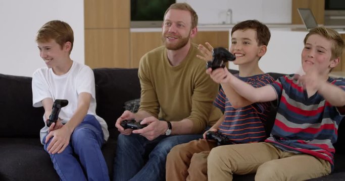Handsome man and three children play on games console in contemporary modern home and complain at referee, in slow motion