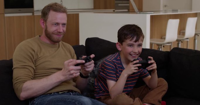 Father and son play games console in contemporary modern home, son is winning