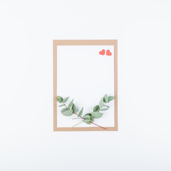 Invitation, greeting, anniversary,  postcard or save the date card or mock up with two red hearts and eucalyptus branches. Minimal concept, top view, flat lay and copy space