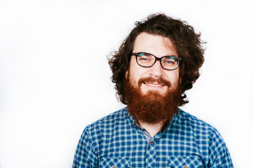 Obraz premium Smiling Bearded man in shirt and eyeglasses looking confident at camera on white background. Portrait of handsome positive young bearded man looking at camera.