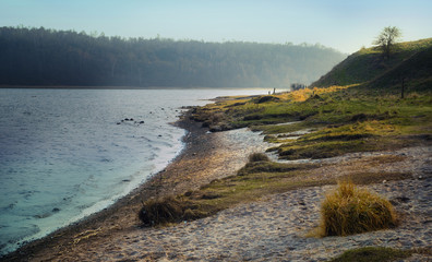 riverbank with beach and grass on a cold morning in early spring, landscape of the river trave near...