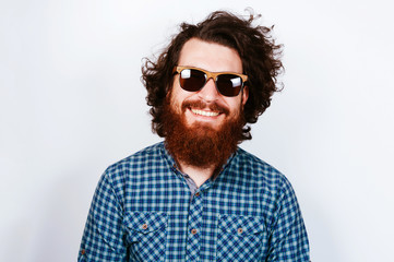 Portrait of young bearded hipster man wearing sunglasses. Happy concept. Smiling man with beard. Curly hair.