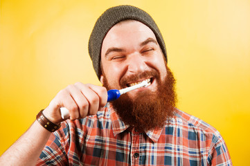 Young hipster man with beard brushing teeth