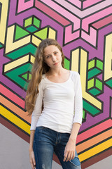 Portrait of a young beautiful girl against the art wall background.