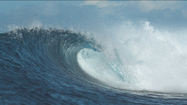 CLOSE UP: Large crystal clear wave breaks on picturesque day at the seaside.