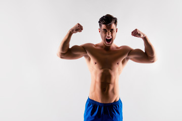 Fototapeta na wymiar Who is number one? I'm number one! Portrait of angry screaming muscular bodybuilder raising arms posing and demonstrating his biceps and triceps, isolated on grey background