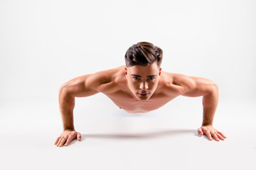 Fototapeta na wymiar Close up photo of a sportive muscular handsome diligent determined athlete doing push ups from the floor, isolated on white background