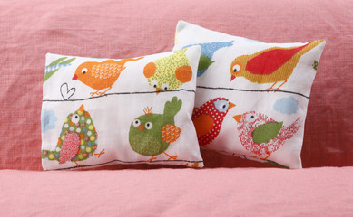 Cheerful pillows with birds on the sofa