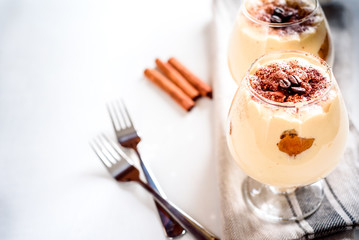 Exquisite Italian dessert tiramisu in cognac glasses on a white