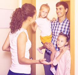 Adults and kids meeting at doorway and greeting one another