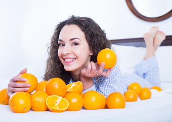 Obraz premium Young brunette with ripe oranges in bed
