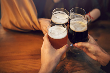 hands of people holding beer and cheering in brewery pub. people toasting with delicious beer  in...