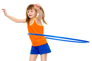 A girl gymnast performs an exercise with a hoop.