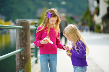Two girls walking down the streets of Hallstatt lakeside town in the Austrian Alps in beautiful...