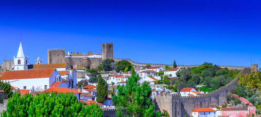 Panoramic view of the beautiful medieval historic center village of Obidos and Castle of Obidos. Wonderful romantic afternoon landscape at sunny weather. District of Leiria, in the centre of Portugal.