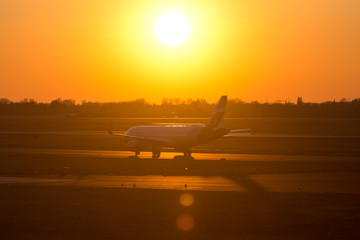 Naklejka na ściany i meble passenger airplane on an airport runway in an evening sundown