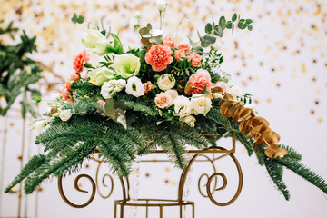 a composition of pistachio, spruce, roses, eustoma, carnations and golden twigs stands on a forged...