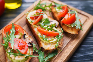 Vegetarian bruschetta with grilled zucchini, fresh tomato and arugula, tasty healthy food close up