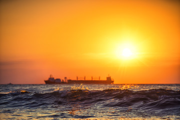 Sun setting at the sea with sailing cargo ship, scenic view