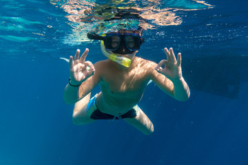 Boy in swimming mask dive in Red sea near yacht