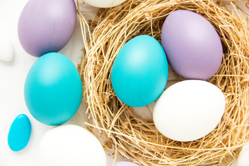 Fototapeta na wymiar colored blue and purple Easter eggs in nest on wooden background, selective focus image. Happy Easter card 