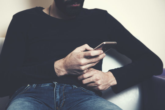 man hand smart phone sitting on sofa