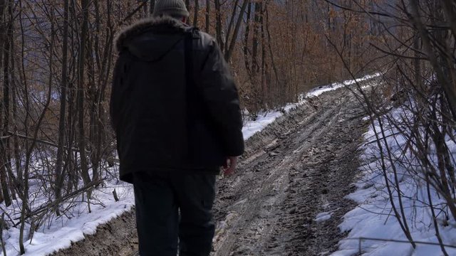 Man goes through the wet forest path snow melted - (4K)