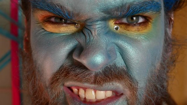 A man with a stage make-up. Portrait of a guy in a blue make-up, native or aboriginal