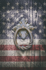 Iron knocker on old wooden door with USA flag