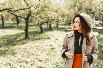 Fototapeta na wymiar Retro style woman in hat walking in the park. Portrait of beautiful lady walking between a trees.
