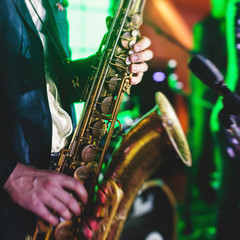 Fototapeta premium Concert view of a saxophone player with vocalist and musical jazz band in the background
