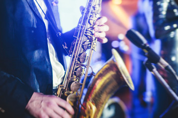 Concert view of a saxophone player with vocalist and musical jazz band in the background