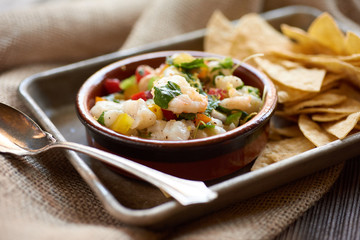 Ensalada y Late Camaron Peruvian Shrimp Salad with Tortilla Chips plated on a tray on burlap and reclaimed wood surface.