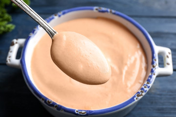 Spoon with tasty creamy sauce for taco over casserole, closeup