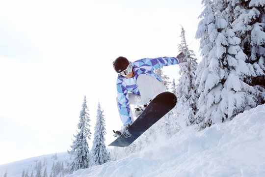 Snowboarder on ski piste at snowy resort. Winter vacation