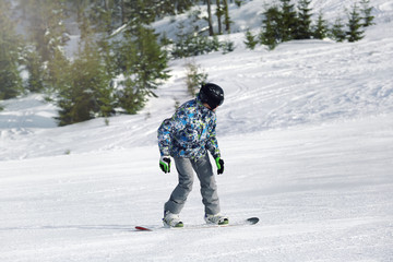 Fototapeta na wymiar Snowboarder on ski piste at snowy resort. Winter vacation