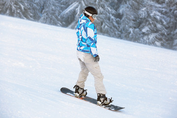 Snowboarder on ski piste at snowy resort. Winter vacation